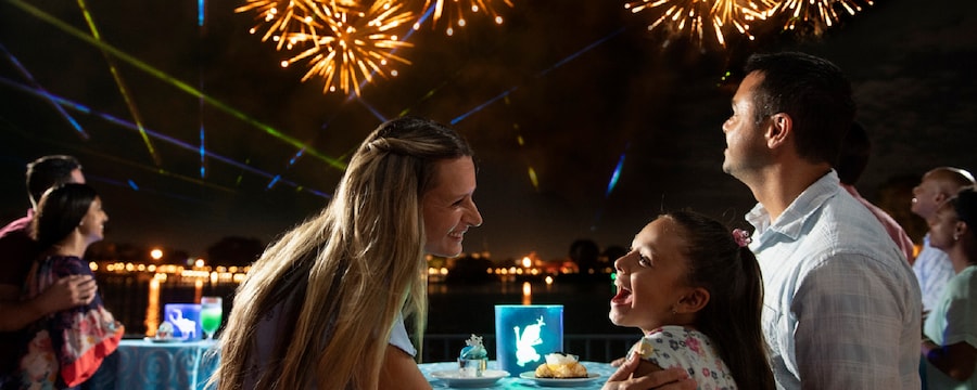 A family watches fireworks while eating dessert