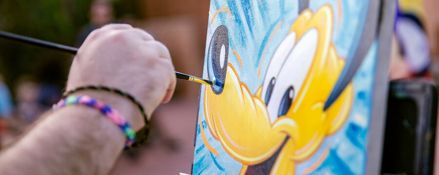 An artist painting Pluto on a canvas