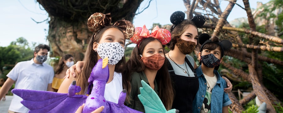 Family with facemasks walk together in Pandora World of Avatar with plush banshees.