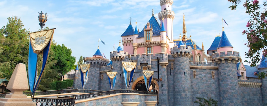 Surrounded by water, Sleeping Beauty Castle features a flag lined bridge leading up to its entrance