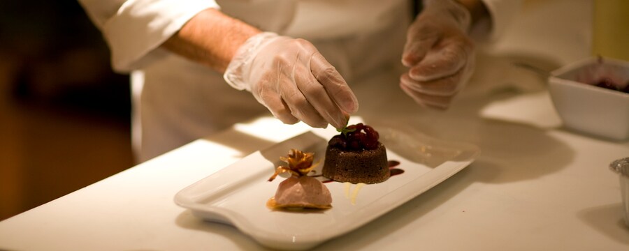 A chef places garnish on two desserts