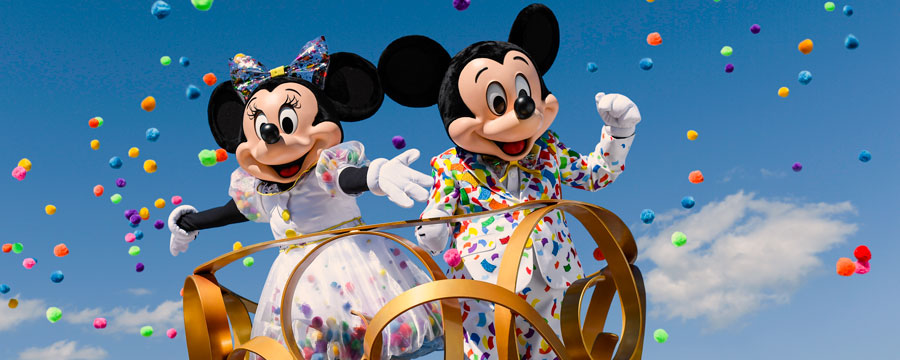 Dressed festively, Mickey Mouse and Minnie Mouse wave from an ornate platform