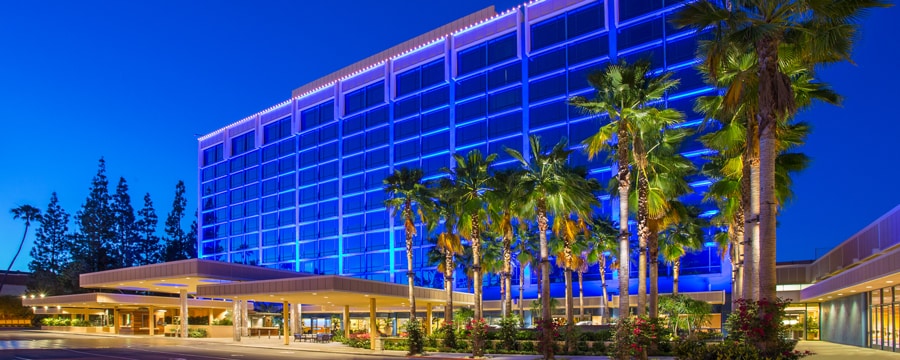 Flanked by palm trees, the modern façade of the Disneyland Hotel glistens against the night sky