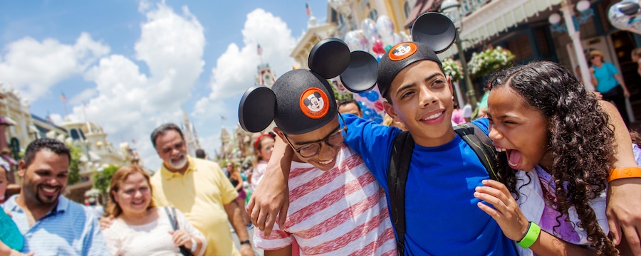 2 garotos adolescentes e uma garota se aconchegam e riem no Walt Disney World Resort enquanto seus pais os observam