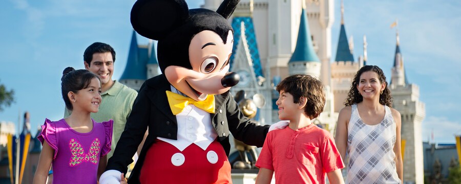 O Mickey Mouse caminhando com 2 crianças e seus pais perto do Cinderella Castle no Magic Kingdom Park