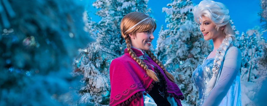 Anna and Elsa hold hands among the icy trees of Arendelle