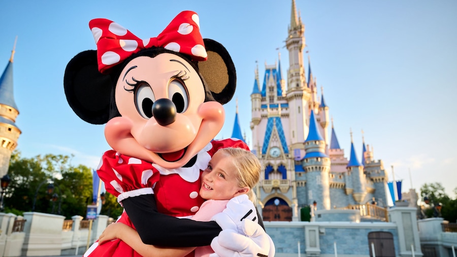 Junges Mädchen umarmt Minnie Maus vor dem Cinderella Castle