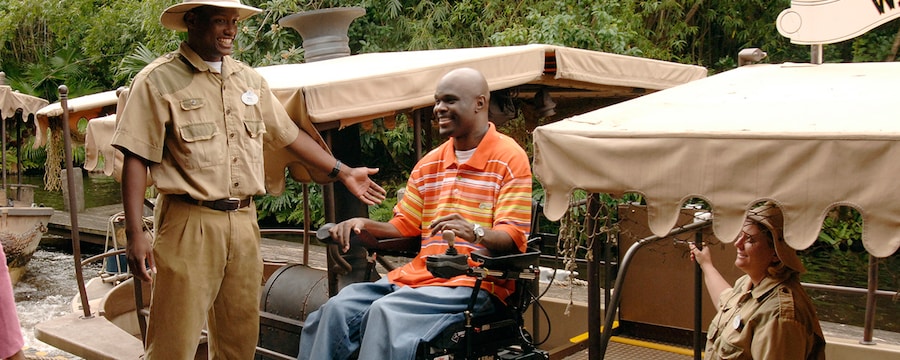 Un hombre en silla de ruedas es ayudado a subir a la atracción de paseo en bote, Jungle Cruise