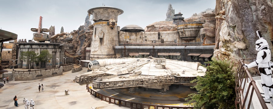Un stormtrooper du Premier Ordre observe le Millennium Falcon amarré sous les bâtiments exotiques de Star Wars et les tours en bois pétrifié