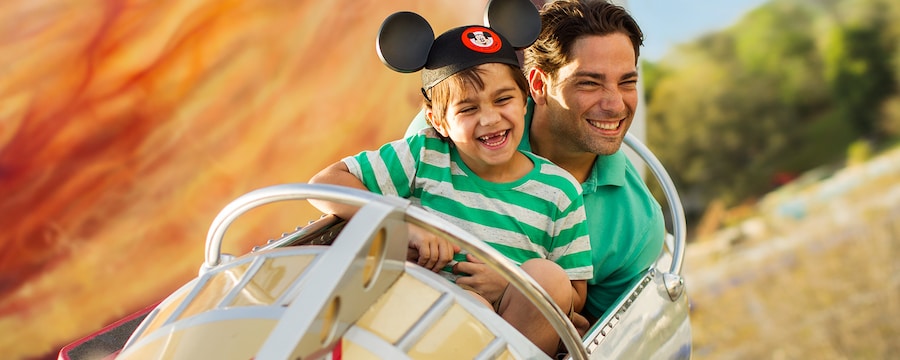 Un papá y su hijo con sombrero de orejas de Mickey, gozan enormemente Astro Orbiter en el parque Magic Kingdom de Walt Disney World Resort