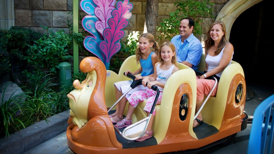 A family of 4 rides inside a giant caterpillar through the Alice in Wonderland attraction.