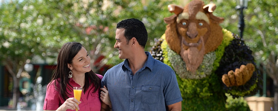 A couple walking in front of a topiary shaped like Beast