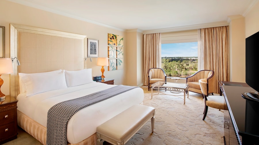 A hotel room with a king bed, a coffee table with chairs and a scenic view