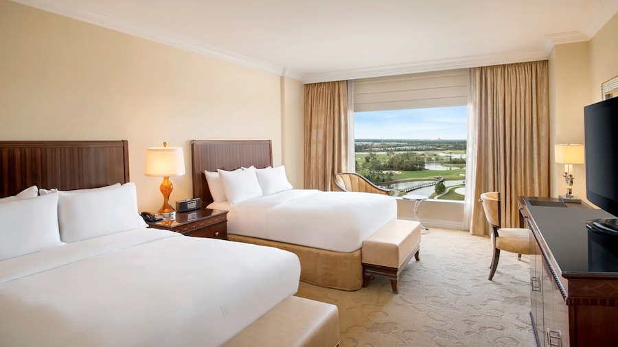 A hotel room with 2 queen size beds and a view of a pool