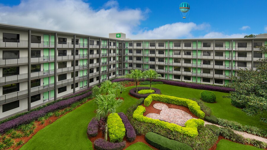 Plusieurs chambres d'hôtel avec des terrasses surplombant une cour et une montgolfière flottant dans le ciel.