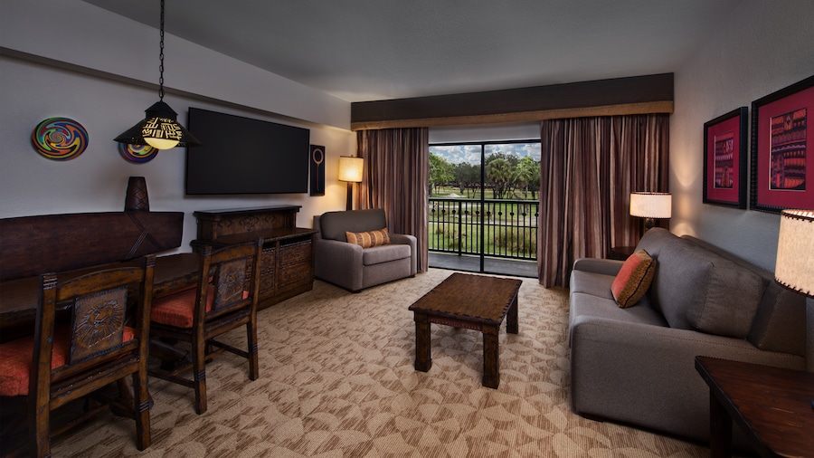 An African-themed living area with a dining table, dresser, TV, chair, couch, coffee table, lamps and wall art