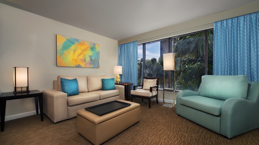 A living area with a couch, an ottoman, a loveseat, a chair, a lamp, a painting and a window