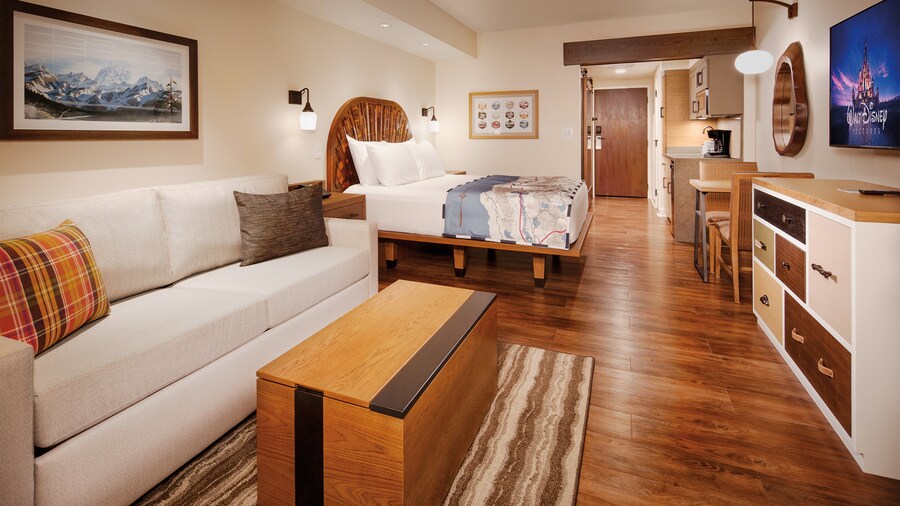 A sofa, coffee table, wall art, bed, dining table for 2, a dresser and TV