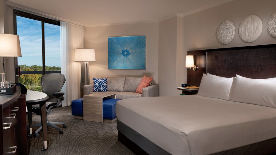 A room with a bed, drawers, a chair, a couch, 2 lamps, a picture and a coffee table