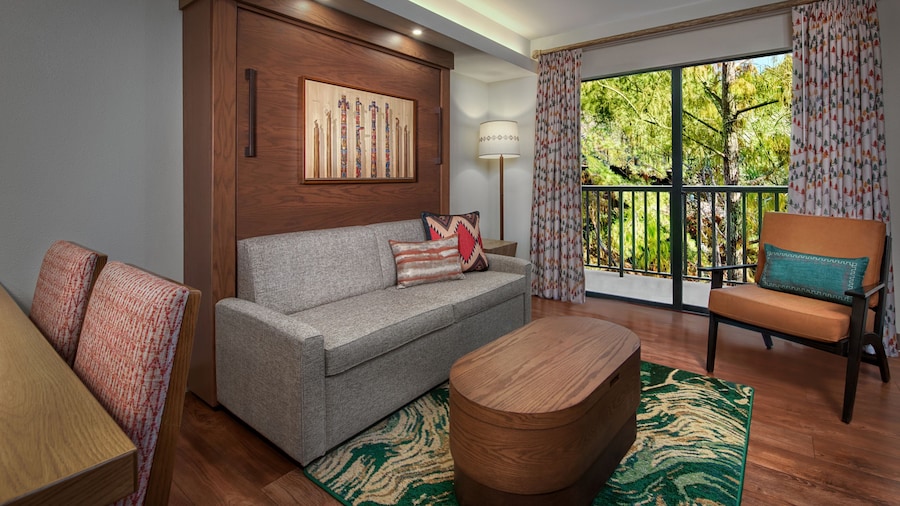 A sitting area with a couch, chair and coffee table overlooking a patio