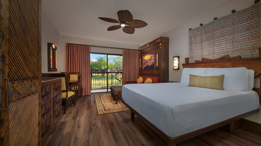 An African inspired room with a king bed, ceiling fan, wall art and balcony