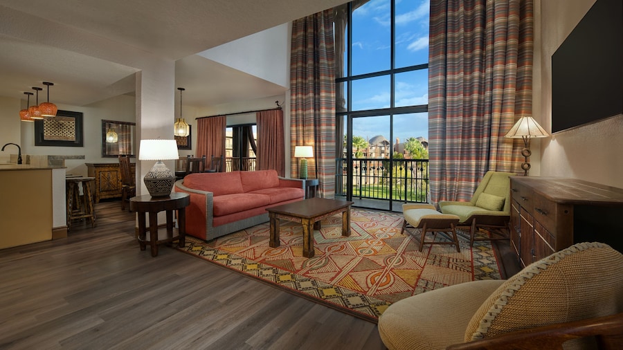 A spacious Villa living room with floor to ceiling windows overlooking a grassy savanna