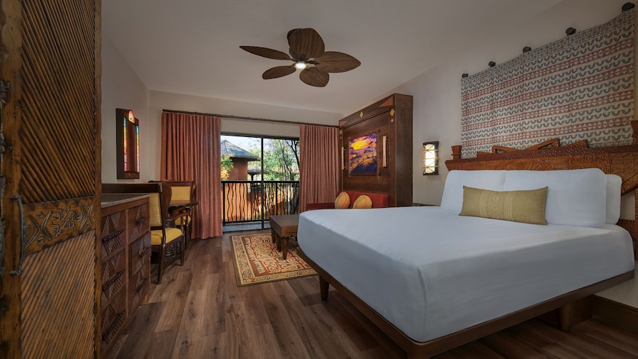 An African inspired room with a king bed, ceiling fan, wall art and balcony