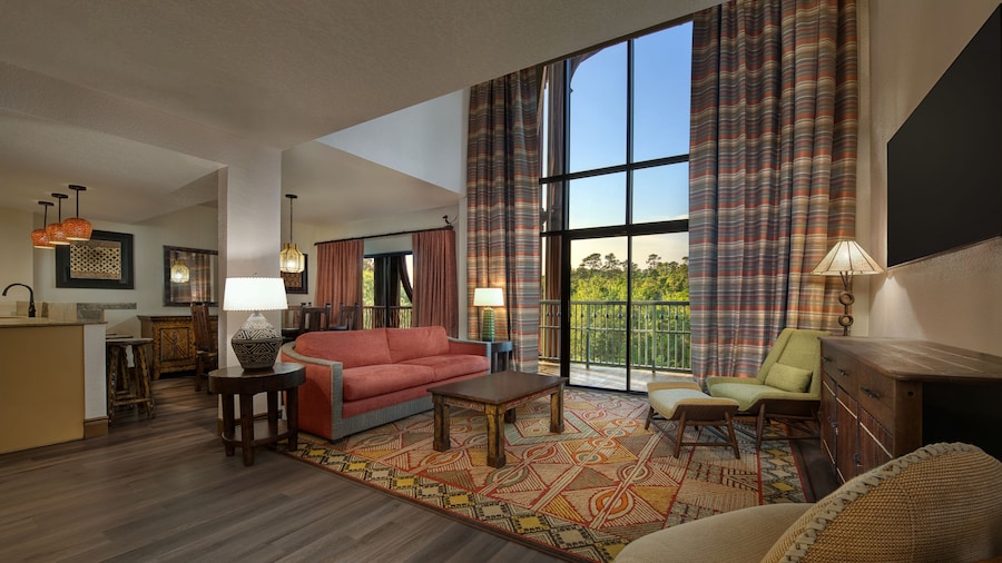 A spacious Villa living room with floor to ceiling windows overlooking a grassy savanna