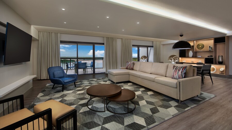 Living area with sofa, arm chairs and a round coffee table in front of a media console with a flat-screen TV