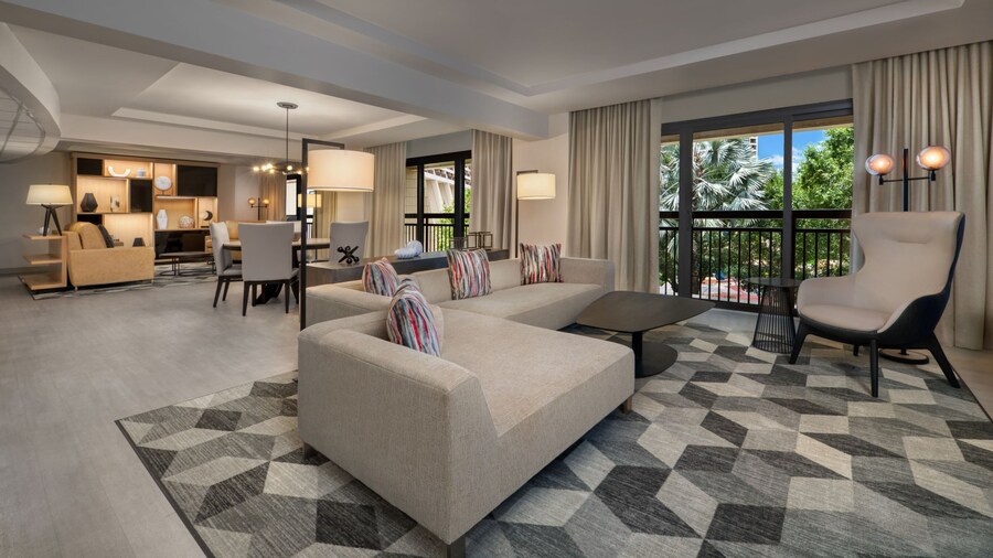 A sitting area with a sofa, easy chair, window, adjacent to a dining and living room areas