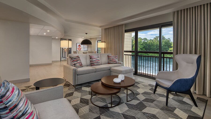 A sleek living room with a sofa, coffee table, easy chair and a large window