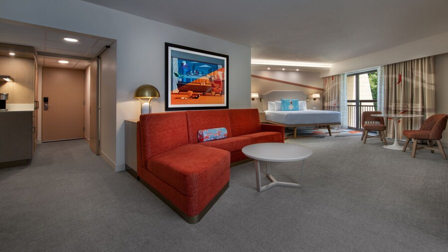 An easy chair, desk and chair, coffee table, sofa, end table and, beyond, a king bed