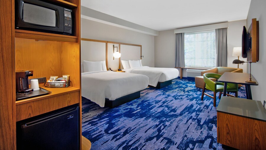 A hotel room at Fairfield Inn by Marriott at Western Entrance with 2 queen beds, a microwave, a mini fridge, a TV, a chair and ottoman and a desk