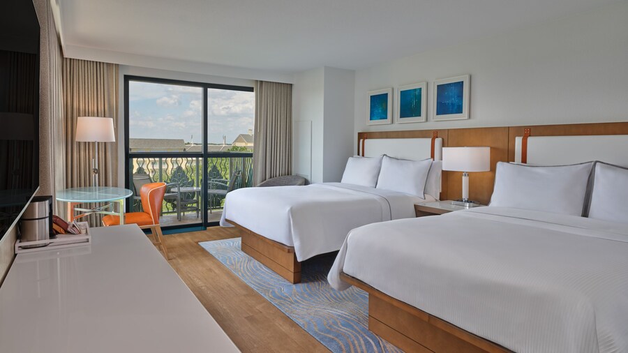 Une chambre d’hôtel avec 2 grands lits, une commode, une table et une chaise, et un balcon au Walt Disney World Swan