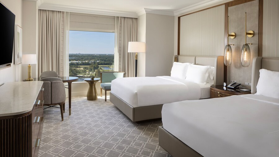 A 2 Queen Beds Premium View Deluxe Room at Waldorf Astoria Orlando with 2 beds, a nightstand, a chair, a desk, a console table, a TV and a window with resort views