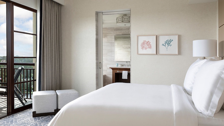 A hotel suite bedroom with a bed, a deck and an en suite bathroom	