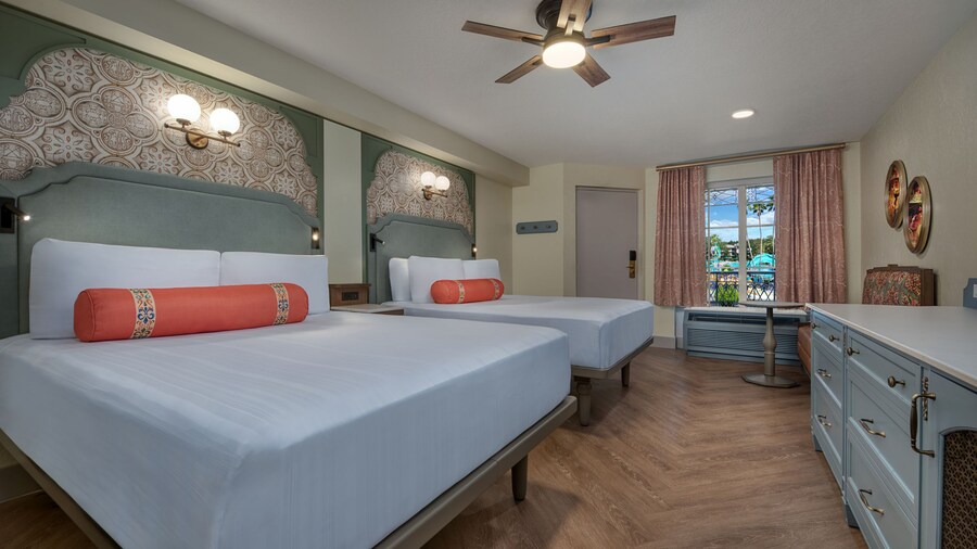 A Disney’s Port Orleans Resort hotel bedroom with a dresser, love seat, ceiling fan and 2 beds