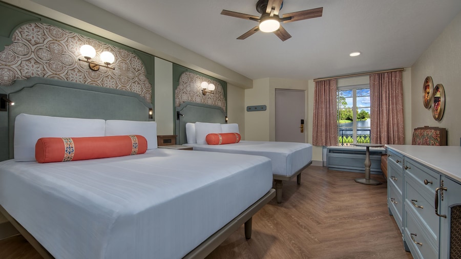 A Disney’s Port Orleans Resort hotel bedroom with a dresser, love seat, ceiling fan and 2 beds