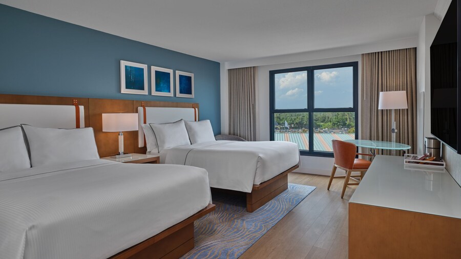 Une chambre d’hôtel avec 2 grands lits, une commode et une table avec une chaise à l’hôtel Walt Disney World Swan