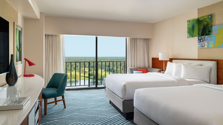 A hotel room with 2 queen beds, a chair and balcony at the Hyatt Regency Grand Cypress Resort