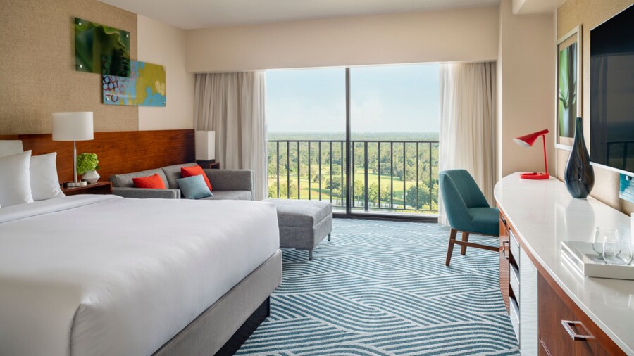 A hotel room with king bed, couch, chair and balcony at the Hyatt Regency Grand Cypress Resort