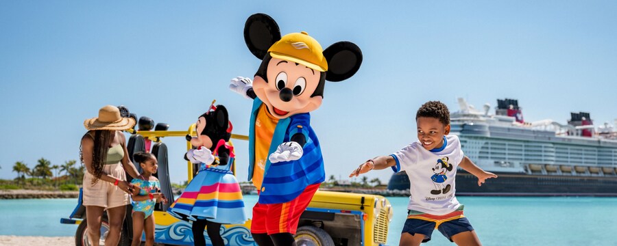 Mickey Mouse and young boy striking surfing poses on a beach while Minnie Mouse greets the family nearby with a Disney cruise ship in the background