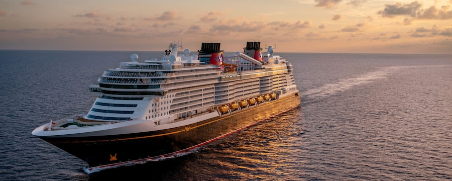 A Disney Cruise Line ship sailing on calm waters at sunset