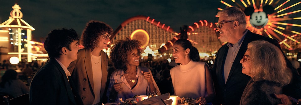 A group of Guests seated around a table overlooking Disney California Adventure Park