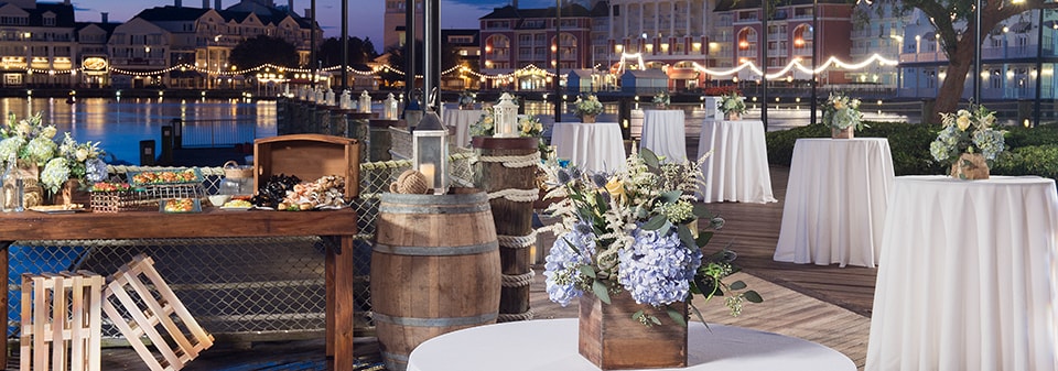 The marina area of Disney’s Yacht Club Resort at dusk, with many small tables featuring flower centerpieces The marina area of Disney’s Yacht Club Resort at dusk, with many small tables featuring flower centerpieces