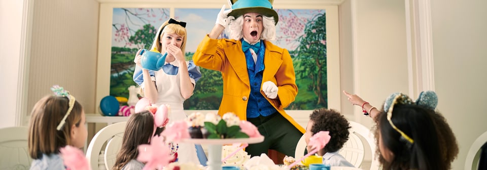 Alice and the Mad Hatter interact with 4 children, who sit at a table set with teacups and cupcakes
