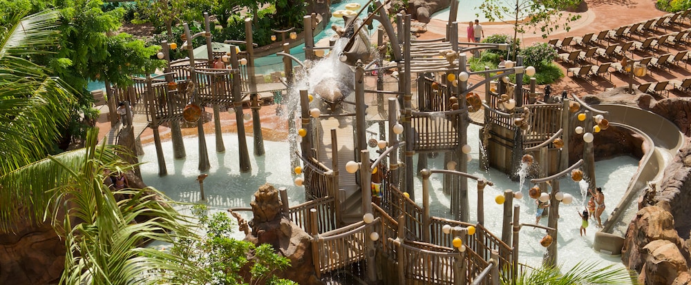 A mother and her children splash about in the water as other young Guests climb the Menehune Bridge