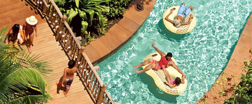 An overhead view of a bridge and a father and daughter on a 2-person inner tube floating down a lazy river