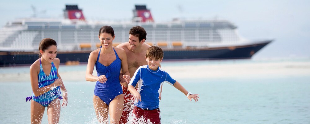 A family of 4 float in the ocean with a tropical island and Disney cruise ship in the background.