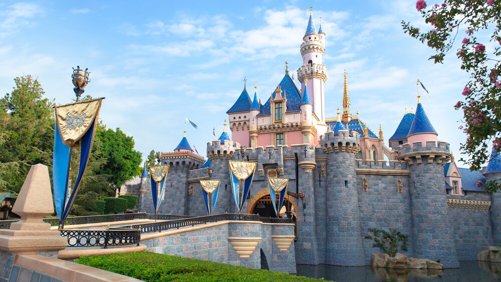 Surrounded by water, Sleeping Beauty Castle features a flag lined bridge leading up to its entrance